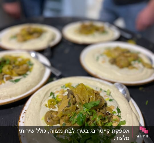 צלחות חומוס עם פטריות ועשבי תיבול מוגשות על שולחן